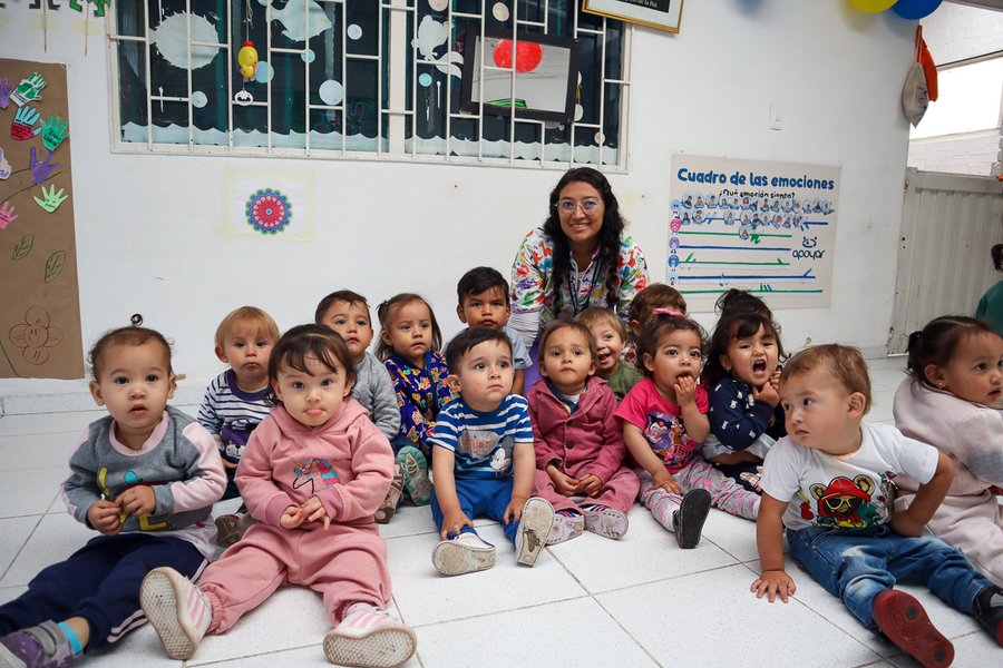 Kita-Erzieherin mit Kindergruppe am Boden sitzend